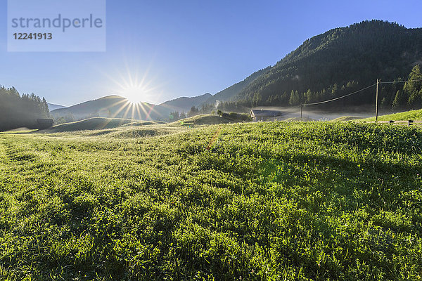 Morgensonne über einer nebligen Bergwiese in den Pragser Dolomiten in der Provinz Bozen (Südtirol)  Italien