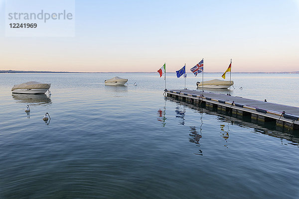 Überdachte Motorboote an der Anlegestelle in der Morgendämmerung am Gardasee (Lago di Garda) bei Bardolino in Venetien  Italien