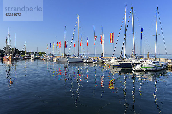 Eine Reihe von Booten und bunten europäischen Flaggen im Hafen von Bardolino am Gardasee (Lago di Garda) in Venetien  Italien