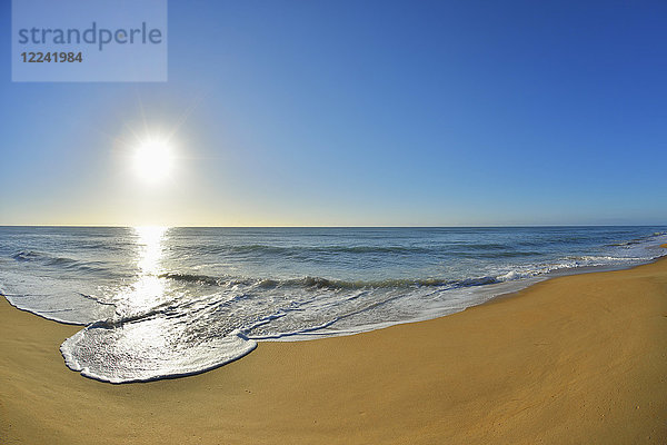 Die Brandung bricht an der Küste des Ninety Mile Beach am Paradise Beach  während die Sonne über dem Meer in Victoria  Australien  scheint.