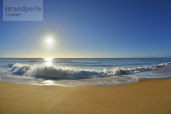 Wellen  die sich an der Küste des Ninety Mile Beach am Paradise Beach brechen  während die Sonne über dem Meer in Victoria  Australien  scheint