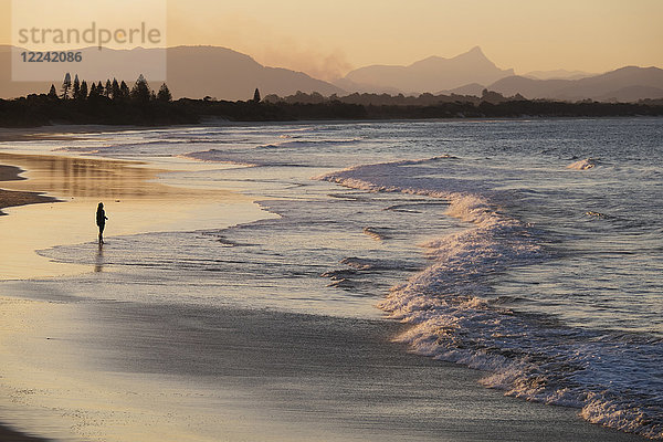 Silhouette einer Person am Strand  die den Wellen am Ufer von Byron Bay in New South Wales  Australien  zuschaut