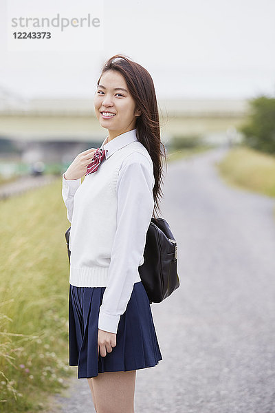 Niedliche japanische Oberschülerin in einem Stadtpark