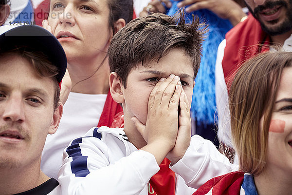 Junge Fußballfans bedecken das Gesicht während des Fußballspiels