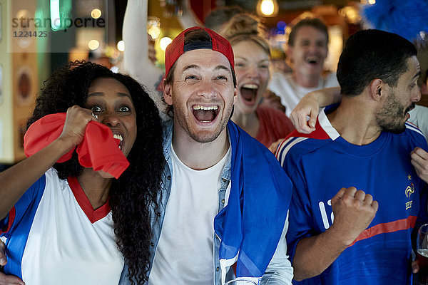 Französische Fußballfans schauen Fußballspiel im Fernsehen in der Kneipe an