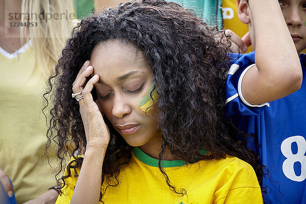 Frau hält Kopf in Enttäuschung beim brasilianischen Fußballspiel