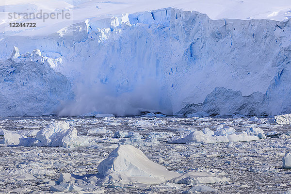 Eislawine  Gletscherkalbung in den mit Eisbergen gefüllten Neko Harbour  frühe Morgensonne  Graham Land  Antarktischer Kontinent  Antarktis  Polarregionen