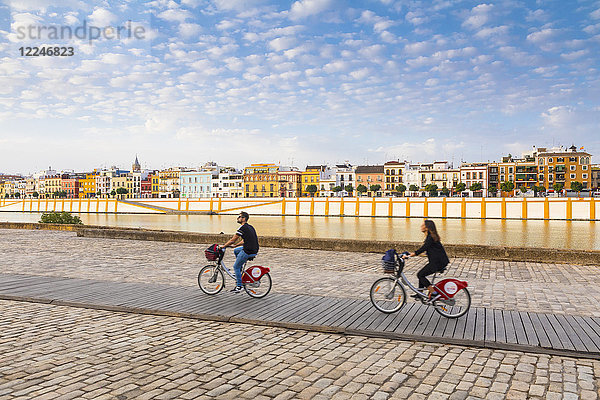Fahrradfahrer am Fluss Rio Guadalquivir  mit dem Stadtteil Triana im Hintergrund  Sevilla  Andalusien  Spanien  Europa
