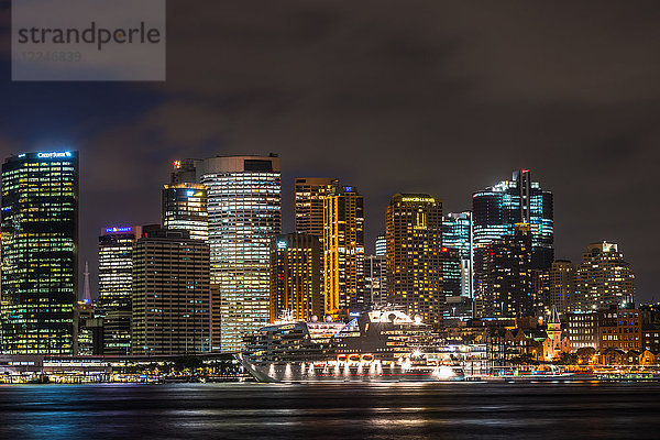 Großes Kreuzfahrtschiff angedockt am Internationalen Terminal im Hafen von Sydney nach Einbruch der Dunkelheit mit Skyline der Stadt  Sydney  New South Wales  Australien  Pazifik