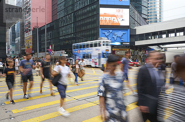 Menschen beim Überqueren einer belebten Straße in Central  dem geschäftigen Einkaufs- und Geschäftsviertel von Hongkong Island  Hongkong  China  Asien