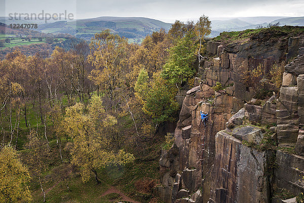 Ein Kletterer erklimmt an einem Herbsttag im Peak District  Derbyshire  England  Vereinigtes Königreich  Europa  eine Felswand  die durch den historischen Abbau im Steinbruch von Bole Hill entstanden ist.