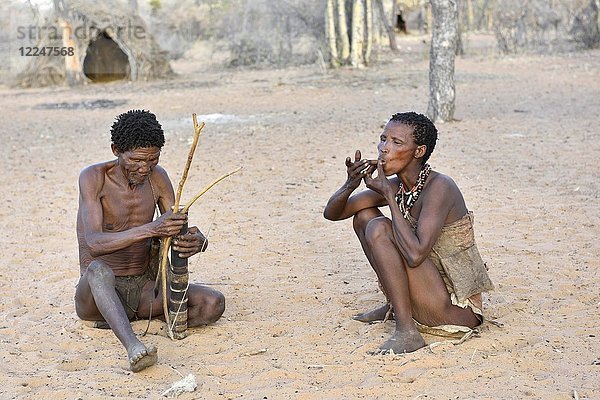 San-Mann mit Pfeil und Bogen und rauchender Frau  Buschmann-Stamm  Kalahari  Namibia  Afrika