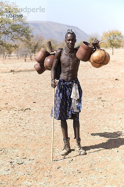 Junger Himba-Mann trägt Lebensmittel auf dem Viehtrieb  Kaokoveld  Namibia  Afrika