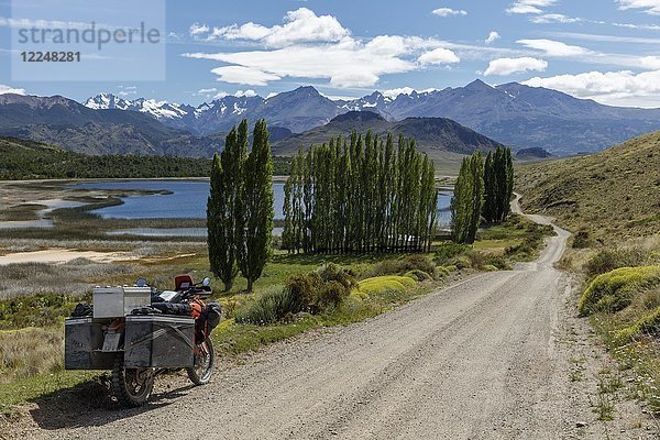 Schwer bepacktes Motorrad auf einer Schotterstraße vor einem See  Valle Chacabuco  Cochrane  Region de Aysen  Chile  Südamerika