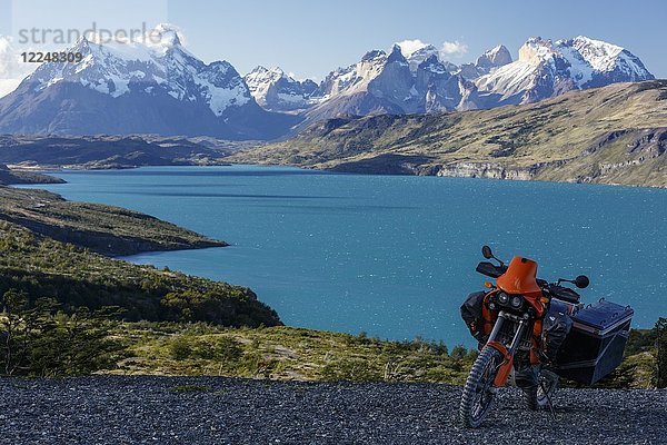 Ein schwer bepacktes Motorrad auf einer Schotterstraße hinter dem Lago del Torro und der Berggruppe Cordillera Paine  Torres de Paine  Region de Magallanes y de la Antartica  Chile.