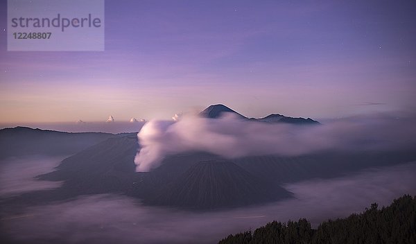 Vulkanlandschaft bei Sonnenaufgang mit Sternenhimmel  rauchender Vulkan Gunung Bromo  mit Mt. Batok  Mt. Kursi  Mt. Gunung Semeru  National Park Bromo-Tengger-Semeru  Java  Indonesien  Asien