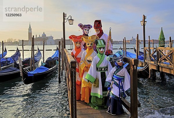 Verkleidete Personen mit venezianischen Masken auf dem Gehweg an der Lagune  hinter der Insel San Giorgio  Karneval in Venedig  Italien  Europa