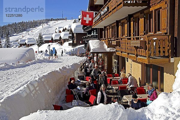 Restaurantterrasse an der Dorfstrasse mit schneebedeckten Häusern  Bettmeralp  Aletschgebiet  Oberwallis  Wallis  Schweiz  Europa