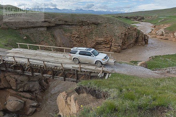 Auto mit Allradantrieb  das eine Holzbrücke über eine wilde Schlucht überquert  Region Issyk Kul  Kirgisistan  Asien