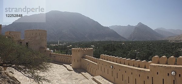 Festung Nakhl mit Rundturm und Zinnen  im Hintergrund das Hajar-Gebirge  Panoramablick  Nakhl  Oman  Asien