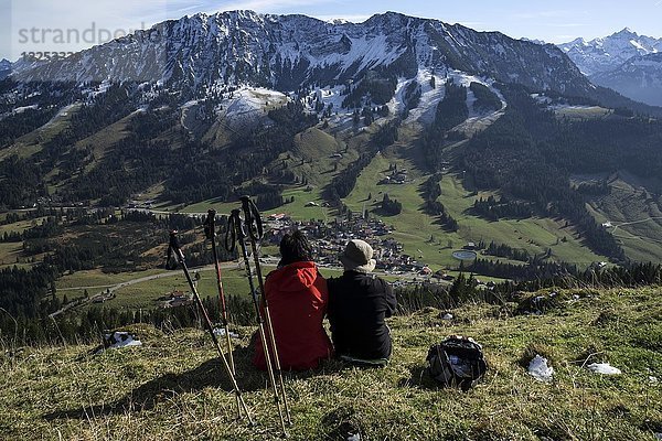 Zwei Wanderer sitzen im Gras und genießen die Aussicht auf Oberjoch und den Iseler  Oberjoch  Allgäu  Bayern  Deutschland  Europa