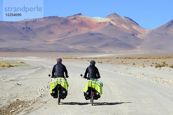 Zwei Radfahrer mit Gepäck fahren auf der Piste der Lagunenroute  Reserva Nacional de Fauna Andina Eduardo Abaroa  Sur Lípez  Potosí  Bolivien  Südamerika
