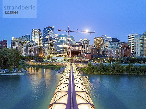 Calgary Downtown in der Abenddämmerung mit beleuchteter Friedensbrücke und Vollmond  Alberta  Kanada  Nordamerika