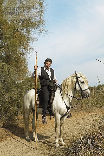 Gardian oder traditioneller Stierhirte in typischer Arbeitskleidung auf einem Camargue-Pferd  Le Grau-du-Roi  Camargue  Frankreich  Europa