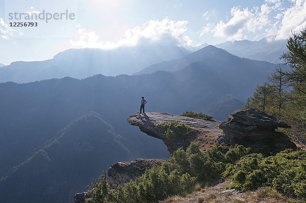 Mann stehend auf markantem Felsvorsprung  Colle San Giovanni bei Elva  Valle Maira  Provinz Cuneo  Cottische Alpen  Piemont  Italien  Europa