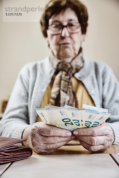 Seniorin sitzt am Tisch und zählt ihr Geld  Deutschland  Europa