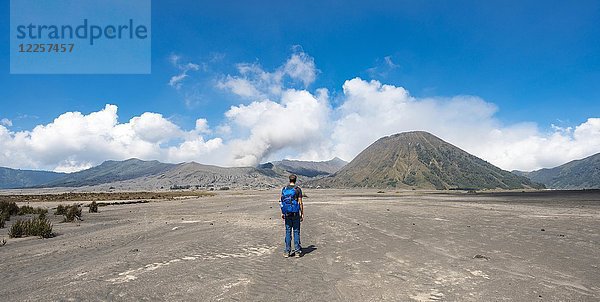 Junger Mann in der Caldera auf dem Weg zum Krater des Gnung Bromo  rauchender Vulkan Gunung Bromo  Mt. Batok  Mt. Kursi  Mt. Gunung Semeru  Tengger Caldera  National Park Bromo-Tengger-Semeru  Java  Indonesien.