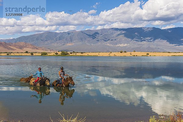 Nomadenkinder auf Pferden beim Überqueren des Tuul-Flusses im Sommer  Gorkhi-Terelj-Nationalpark  Mongolei  Asien