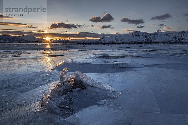 Gebrochenes Eis  gefrorener Fjord mit Bergen bei Sonnenuntergang  Sonnenreflex  Gimsoy  Lofoten  Norwegen  Europa