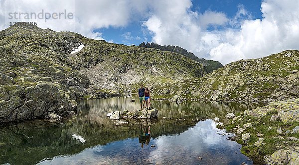 Paar Wanderer steht auf einem Stein in einem kleinen See  Klafferkessel  Schladminger Höhenweg  Schladminger Tauern  Schladming  Steiermark  Österreich  Europa