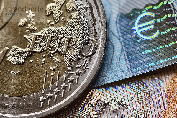 Symbolbild  Standbild  Währung  Euro-Münze und Hologramm eines Euro-Zeichens auf 20-Euro-Schein  Detail