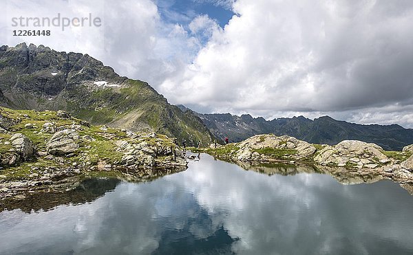 Wanderer spiegeln sich in einem See  Klafferkessel  Schladminger Höhenweg  Schladminger Tauern  Schladming  Steiermark  Österreich  Europa