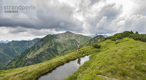 Wanderer spiegelt sich in einem kleinen See  Schladminger Höhenweg  Schladminger Tauern  Schladming  Steiermark  Österreich  Europa