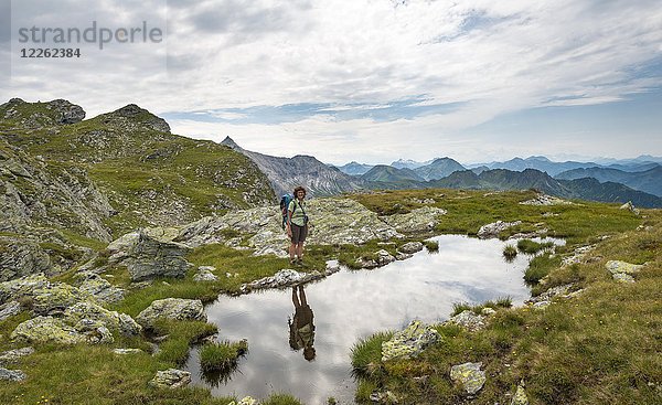 Wanderer spiegelt sich in einem kleinen See  Schladminger Höhenweg  Schladminger Tauern  Schladming  Steiermark  Österreich  Europa