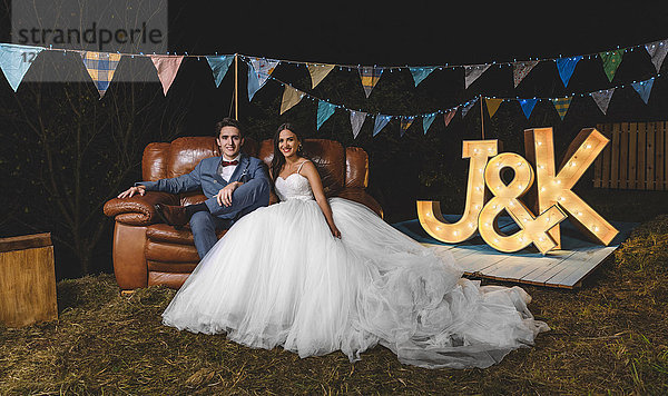 Porträt eines glücklichen Hochzeitspaares auf dem Sofa auf einer Nachtfeld-Party