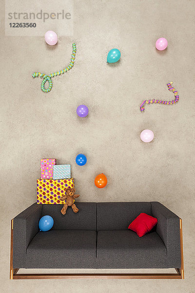 Ballons und Luftschlangen mit Geschenken auf der Couch