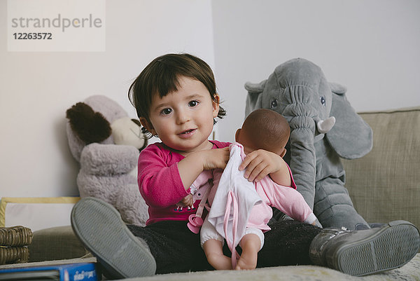 Porträt eines lächelnden Mädchens  das zu Hause mit einer Puppe spielt.