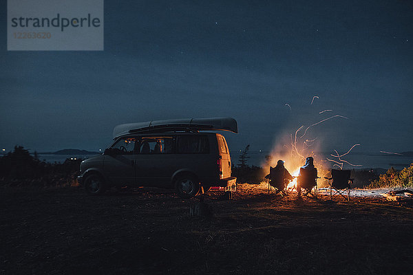 Kanada  British Columbia  Prinz Rupert  zwei Männer sitzen nachts am Lagerfeuer im Minivan.