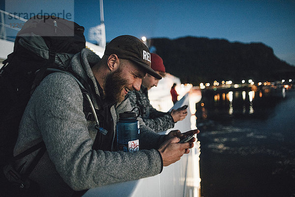 Kanada  British Columbia  zwei Männer auf einem Boot  die nachts Mobiltelefone benutzen.
