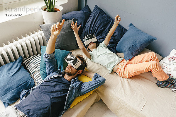 Vater und Sohn mit VR-Brille zu Hause liegend