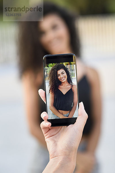 Frau fotografiert ihre Freundin mit Handy  Nahaufnahme