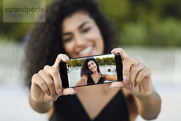 Glückliche junge Frau nimmt Selfie mit Handy  Nahaufnahme