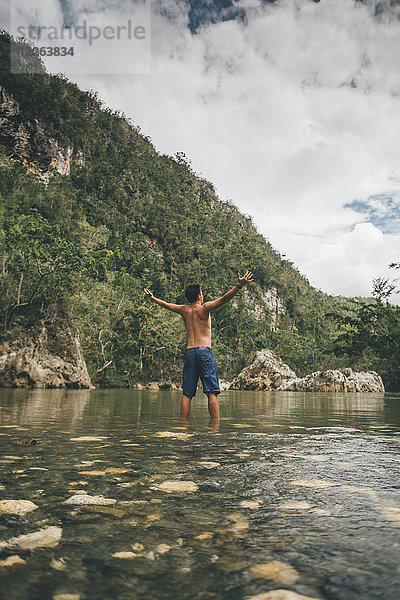 Kuba  Baracoa  Junger Mann im Yumuri Fluss  Rückansicht