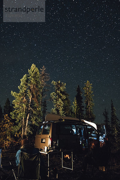 Kanada  British Columbia  zwei Männer sitzen nachts unter dem Sternenhimmel im Minivan.