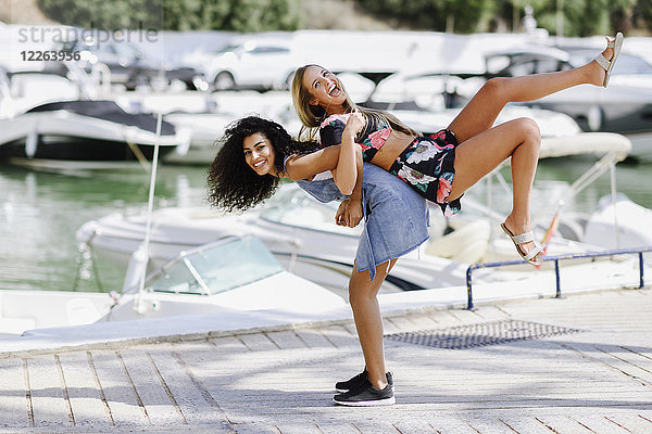 Zwei verspielte junge Frauen an der Uferpromenade im Sommer