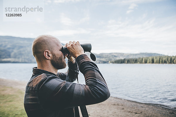 Kanada  British Columbia  Mann schaut durchs Fernglas am Cultus Lake